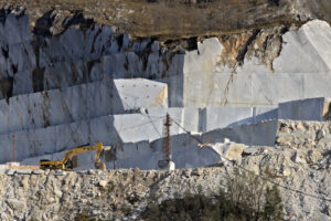 Excavator. Apuan Alps, Carrara, Tuscany, Italy. March 28, 2019.  An excavator in a quarry of white Carrara marble. - MyVideoimage.com | Foto stock & Video footage