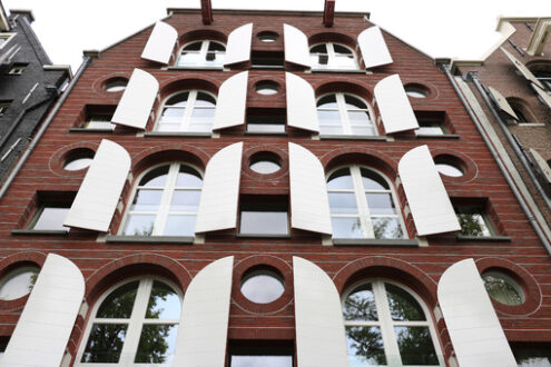 Facade of a brick house with white windows and shutters. - MyVideoimage.com