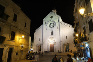 Facade of the Cathedral of San Sabino in Bari in limestone. Night shot with people walking. Foto Bari photo.