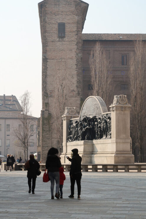 Family with child and people walking in piazza della Pace in parma. In the background the monument to Giuseppe Verdi and the Palazzo della Pilotta. - MyVideoimage.com