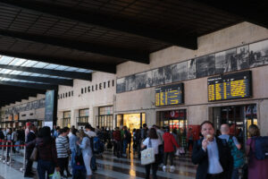 Florence train station with people walking. Scoreboards for arriving and departing trains. Project of the Tuscan Group with the Architect Giovanni Michelucci. - MyVideoimage.com