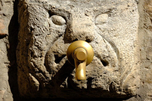 Fountain with brass faucet applied on an ancient mask carved on stone. - MyVideoimage.com