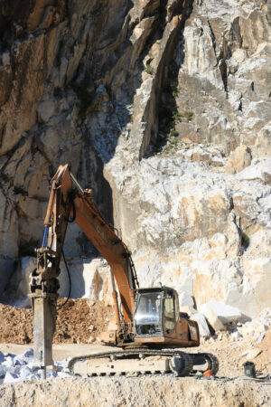 Grande escavatore in cava di marmo a Carrara. Excavator with demolition hammer in a Carrara marble quarry. Cave marmo. - MyVideoimage.com | Foto stock & Video footage