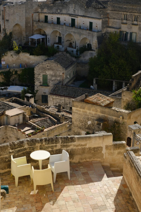 Hotel a  Matera nei vecchi Sassi. Roofs of houses in the Sassi of Matera transformed into hotels. Panoramic terrace with sofa and chair in white plastic. - MyVideoimage.com | Foto stock & Video footage