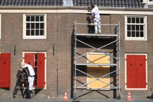 House painter paints a house. Facade with brick wall and white w - MyVideoimage.com