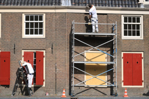 House painter paints a house. Facade with brick wall and white w - MyVideoimage.com