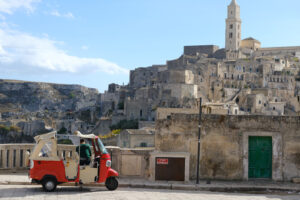 Italian taxi Red taxi made with a Piaggio APE. In the background the city of Matera. - MyVideoimage.com | Foto stock & Video footage