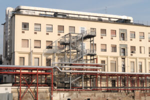 Major hospital, polyclinic. Implant piping resting on a steel structure. Fence of the construction site for the construction of the new hospital. - MyVideoimage.com | Foto stock & Video footage