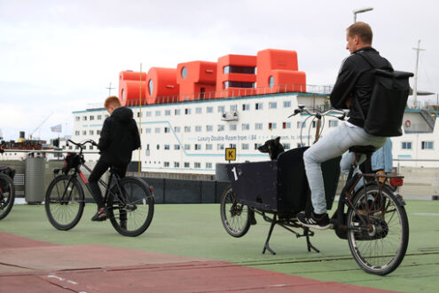 Man and black dog on a bicycle await the ferry. In the backgroun - MyVideoimage.com