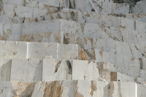 Marble quarry in Carrara. White Carrara marble quarry in Tuscany. Mountains of the Apuan Alps, blue sky and a mechanical excavator. - MyVideoimage.com | Foto stock & Video footage