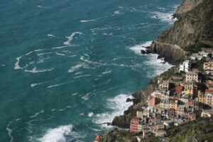 Mare a Riomaggiore. Panorama of the village of Riomaggiore in the Cinque Terre. Rough sea with waves on the cliff. - MyVideoimage.com | Foto stock & Video footage