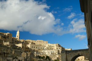 Matera Italy panorama. Panorama of the Sassi of Matera with houses in tuff stone. Church with bell tower and stone arch at dawn with sky and clouds. - MyVideoimage.com | Foto stock & Video footage