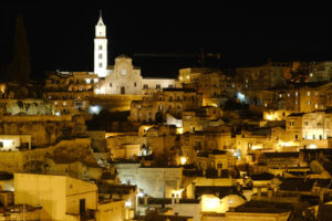 Matera di notte. Night panorama of the city of Matera in Italy. Streets, church with bell tower and houses illuminated by artificial yellow lights. - MyVideoimage.com | Foto stock & Video footage