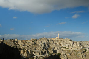 Matera houses. Panorama of houses and of the Sassi of Matera with roofs and streets. Blue sky with church and bell tower with blue sky background with clouds. - MyVideoimage.com | Foto stock & Video footage