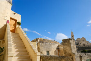 Mediterranean courtyard. Matera alley with staircase and church. A Mediterranean courtyard with leaves of a small tree blowing in the wind. - MyVideoimage.com | Foto stock & Video footage