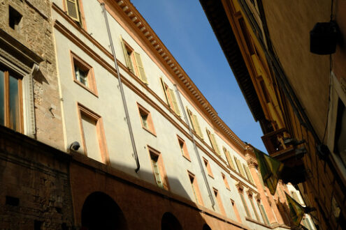 Narrow historic street in Foligno with flags on the facades of the houses. Glimpse in the historic center of the Umbrian town with wind. - MyVideoimage.com | Foto stock & Video footage