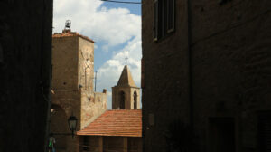 Narrow street with clock tower and bell tower in Castiglione della Pescaia. An ancient village in the Tuscan Maremma built on a hill facing the sea. - MyVideoimage.com | Foto stock & Video footage