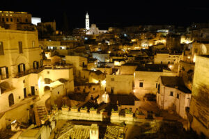 Notturno a Matera. Night panorama of the city of Matera in Italy. Streets, church with bell tower and houses illuminated by artificial yellow lights. - MyVideoimage.com | Foto stock & Video footage