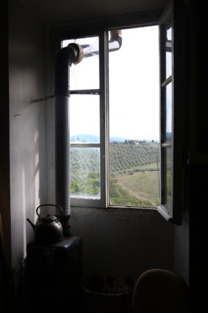 Old artist’s studio window with the backdrop of the hills of Florence. In the foreground a charcoal stove with kettle placed on top. - MyVideoimage.com