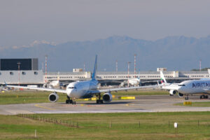 Oman Air Airbus A330-243  airplane on the Malpensa airport runway. In the background the buildings and Air Italy airplane. - MyVideoimage.com