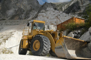 Pala meccanica in cava di marmo. Large mechanical shovel in a quarry of white Carrara marble. Blocks of white marble deposited in the square. - MyVideoimage.com | Foto stock & Video footage