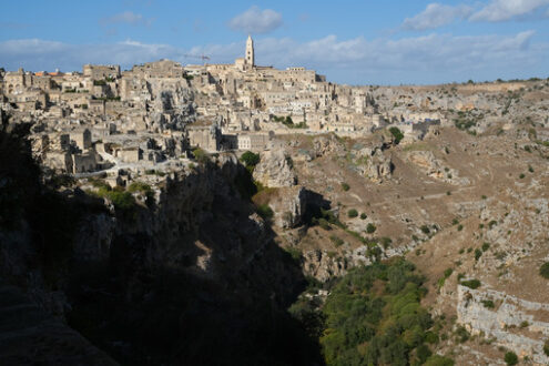 Panorama di Matera con case e chiesa. Panorama of houses and of the Sassi of Matera with roofs and streets. Blue sky with church and bell tower with blue sky background with clouds. - MyVideoimage.com | Foto stock & Video footage