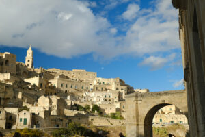 Panorama di Matera. Panorama of the Sassi of Matera with houses in tuff stone. Church with bell tower and stone arch at dawn with sky and clouds. - MyVideoimage.com | Foto stock & Video footage