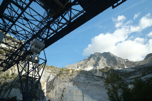 Cava di marmo Carrara. Panoramic view of the Apuan Alps from a quarry of white Carrara marble. A large overhead crane used to move marble blocks.