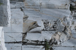 Parete di marmo bianco in cava. Wall of a white marble quarry under the mountain. Foto stock royalty free. - MyVideoimage.com | Foto stock & Video footage