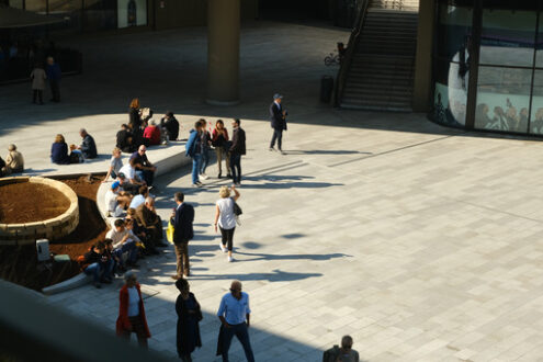 Pedestrian square in Milan. Piazza with entrance to the Citylife shopping center in Milan. People sitting on stone benches and walking. - MyVideoimage.com | Foto stock & Video footage