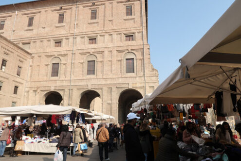 People at the Parma market in Piazza della Pace. Brick arch of the Palazzo della Pilotta. - MyVideoimage.com