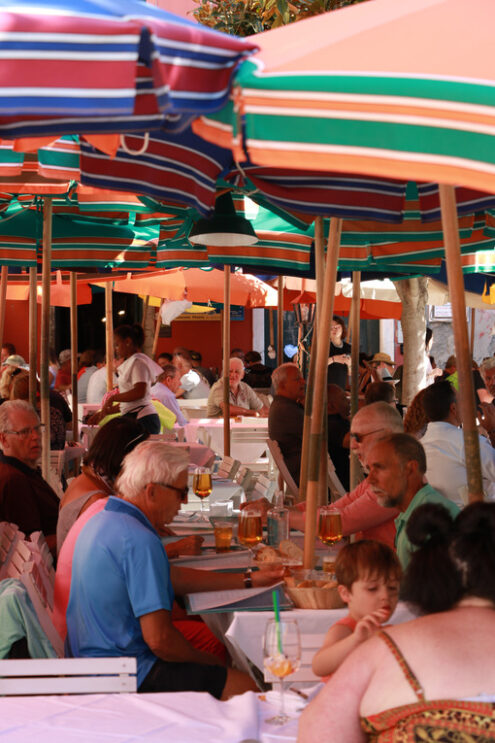 People at the restaurant in Italy. Cinque Terre. Many people sitting at tables, under colored umbrellas, in a restaurant in the village of Vernazza in the Cinque Terre. - MyVideoimage.com | Foto stock & Video footage