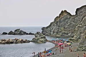 Persone al mare delle Cinque Terre. Levanto. Alcune persone si abbronzano al sole. Sullo sfondo la scogliera. - MyVideoimage.com | Foto stock & Video footage