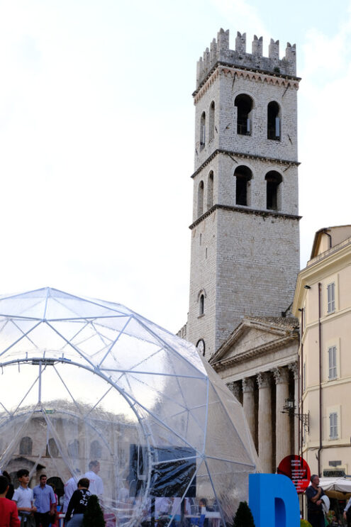 Piazza del comune di Assisi with the civic tower, the temple of Minerva and a geodesic dome with a reticular structure. - MyVideoimage.com
