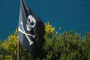 Pirate flag hoisted on the hills of the Cinque Terre in Liguria. In the background the sea. - MyVideoimage.com | Foto stock & Video footage