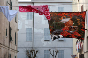 Quartiere popolare. Lenzuola decorate con immagini appese ad asciugare su un filo teso tra due edifici a La Spezia. - MyVideoimage.com | Foto stock & Video footage