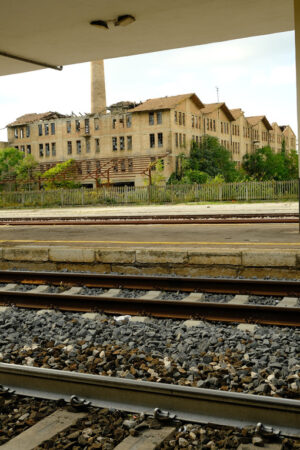 Railway station with tracks and in the background an old abandoned factory. Foto Stazione. Station photo