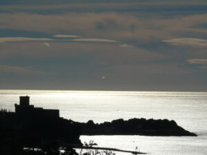 Riflessi sul mare. Silhouette of the castle of Lerici at sunset. Sky with clouds and sea of gold color. Foto sfondo mare. - MyVideoimage.com | Foto stock & Video footage