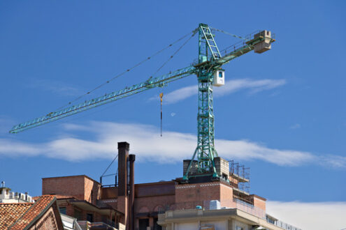 Ristrutturazione edificio a Milano. Construction crane mounted on the roof of a building in Milan. Cantieri edili. - MyVideoimage.com | Foto stock & Video footage