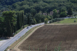 Road with cars on the Chianti hills. Cultivated fields and farmhouses in the Tuscan countryside near Florence. - MyVideoimage.com