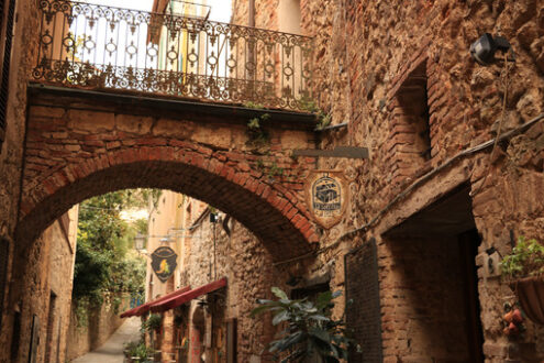 Romantic restaurants in a street of Massa Marittima. An alley with restaurant signs and tables with chairs. - MyVideoimage.com | Foto stock & Video footage