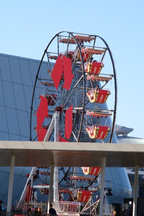 Ruota panoramica a Milano Citylife. Ferris wheel with arrows symbols at the three Citylife towers in Milan. Between the mall and the skyscrapers a small ferris wheel. - MyVideoimage.com | Foto stock & Video footage