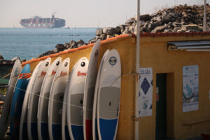 Sailboat. Surfboards placed on the shore and a container ship in the background. - MyVideoimage.com | Foto stock & Video footage