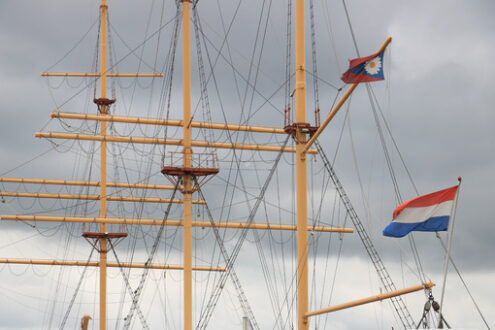 Sailing ship masts with Dutch flag. Sky background with clouds. - MyVideoimage.com