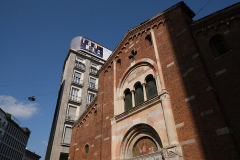 San Babila Milan. Brick facade of the church of San Babila in Milan. On the facade a mosaic. In the background modern buildings. - MyVideoimage.com | Foto stock & Video footage