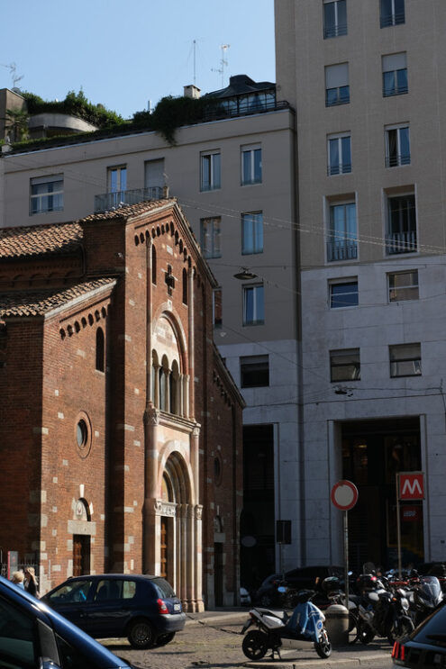 San Babila Milano. Brick facade of the church of San Babila in Milan. On the facade a mosaic. In the background modern buildings. - MyVideoimage.com | Foto stock & Video footage