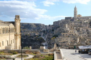 Sant’Agostino Matera. Convent of Sant’Agostino in Matera. Beige stone facade. In the background the city with the church and the bell tower. - MyVideoimage.com | Foto stock & Video footage