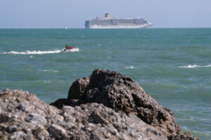 Sea cliff with waves and cruise ship. The waves of the Ligurian sea crash on the rocks. - MyVideoimage.com | Foto stock & Video footage