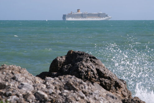 Sea cliff with waves and cruise ship. The waves of the Ligurian sea crash on the rocks. - MyVideoimage.com | Foto stock & Video footage