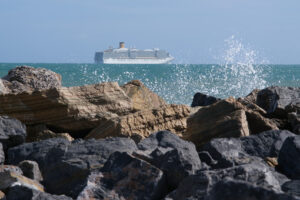 Sea cliff with waves and cruise ship. The waves of the Ligurian sea crash on the rocks. - MyVideoimage.com | Foto stock & Video footage